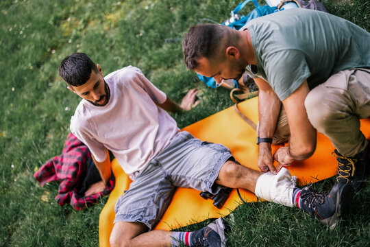 Two hikers providing first aid to an injured companion outdoors