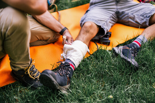 Close-up of a hiker receiving an ankle bandage during an outdoor trip