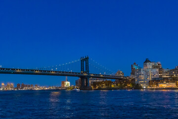 Fototapeta premium Bright lights of Manhattan Bridge shimmering over the East River at twilight