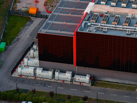 Aerial view of a modern datacenter facility featuring rooftop cooling units, solar panels, and external power infrastructure in Rome, Lazio, Italy.