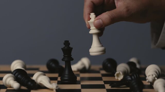 business hand holding a white chess king taking black king, checkmate concept