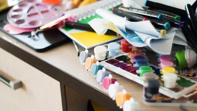 Creative mess with messy paint brushes and multi-colored paints on artist tabletop