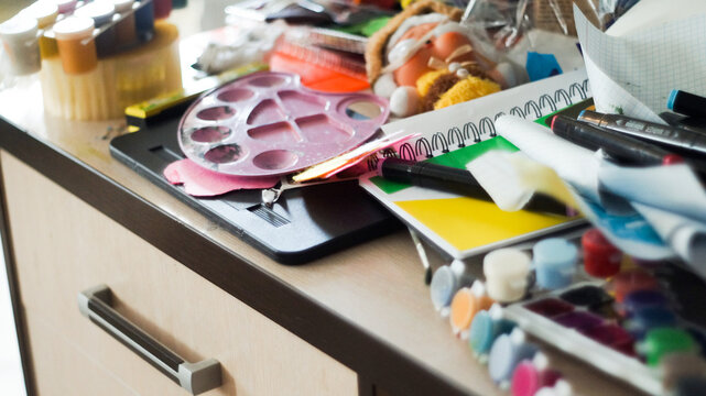 Creative mess with messy paint brushes and multi-colored paints on artist tabletop
