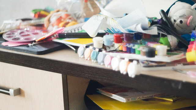 Creative mess with messy paint brushes and multi-colored paints on artist tabletop