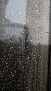 Raindrops on window glass surface as abstract moody background