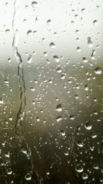 Raindrops on window glass surface as abstract moody background