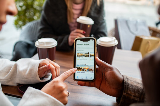 Friends using travel app on smartphone at coffee shop table