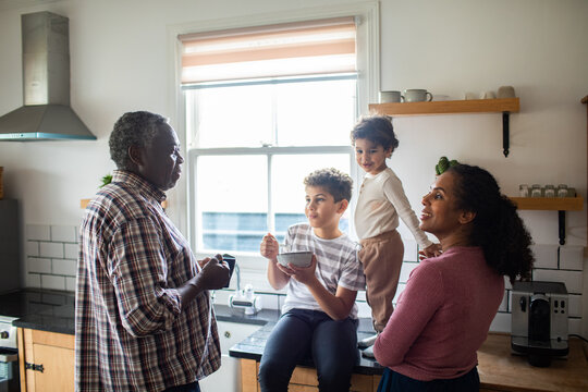 Grandfather chatting with mother and children in sunny home kitchen