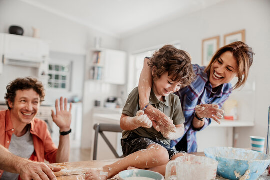 Parents and young son baking together in home kitchen