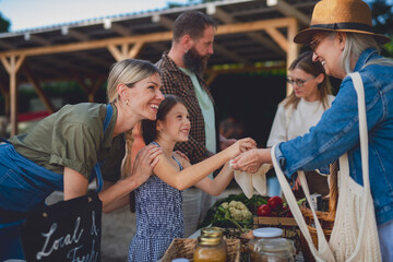 Fototapeta premium People shopping for fresh organic produce at local farmers market.