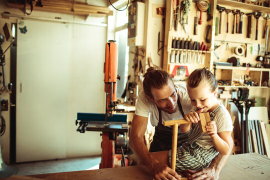 Father teaching daughter woodworking in home workshop