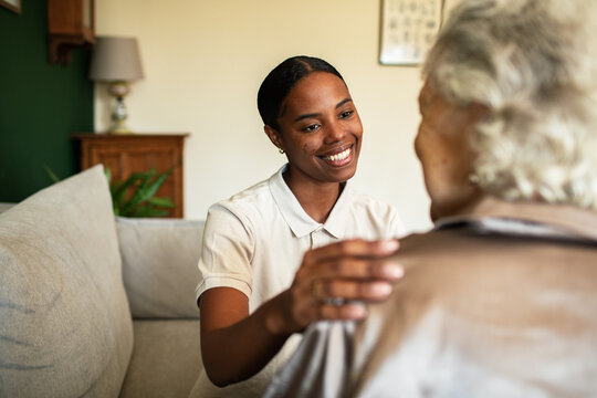 Smiling caregiver comforting senior woman at home
