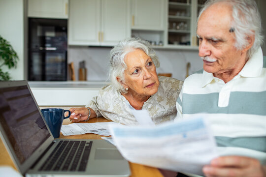Senior couple reviewing bills and finances at home kitchen
