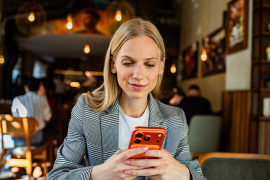 Young businesswoman using smartphone in cozy cafe