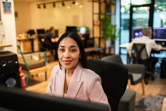 Confident businesswoman at computer in modern coworking office