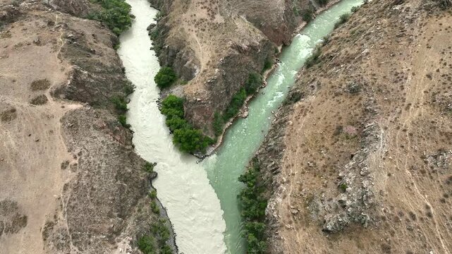 Aerial view of the river confluence in Chong-Kemin National Park with rocky canyon walls and lush green trees in Shabdan, Chuy Province, Kyrgyzstan.