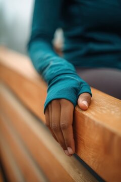 Hand resting on wooden bench highlights connection to nature. Soft colors and blurred background create peaceful atmosphere. Ideal for wellness or lifestyle themes