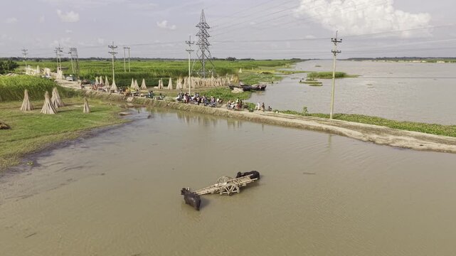 Water buffalo with a traditional bamboo cart near a rural riverbank in Bangladesh, surrounded by muddy water, green vegetation, boats and countryside landscape, representing traditional transportation
