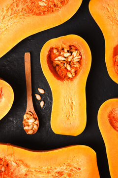 Repeating pattern of sliced squash on dark background with natural texture. Modern autumn backdrop with pumpkin and healthy food concept. Top view