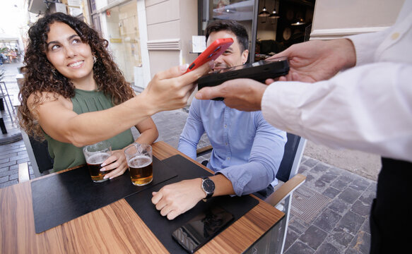 A woman smiles as she pays the bar tab