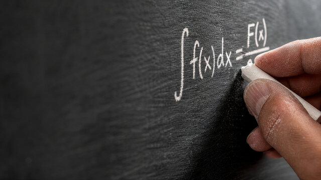 Teacher Hand Writing Math Formula with Chalk on Slate Board - Academic Pedagogy Macro - University Course Background - Warm Overhead Lighting