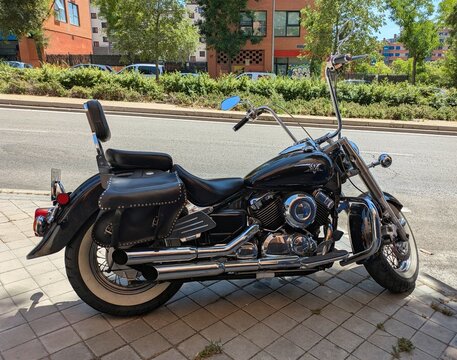 Vista lateral de moto Yamaha XVS 650 Drag Star con alforjas de cuero y manillar alto, estacionada en Madrid, Espa&ntilde;a, 11 de junio de 2026
