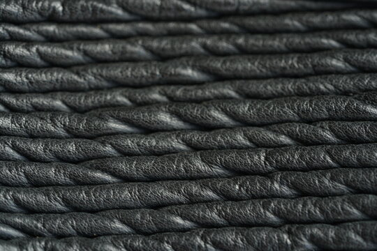 Black genuine leather biker jacket texture background Macro close-up of black genuine leather biker jacket texture with natural grain, wrinkles and stitched details. Dark leather surface creates a sty