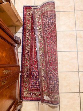 Partially rolled antique Persian wool runner rug on tiled floor