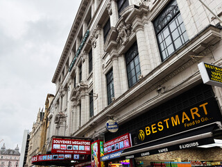 Naklejka premium Busy souvenir and convenience shopping Coventry street in London, UK with crowds outside Bestmart and souvenirs megastore