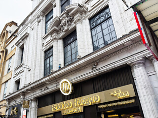 Naklejka premium Busy London street scene with Haidilao Huoguo restaurant frontage and shoppers outside a historic white tiled building in London, UK