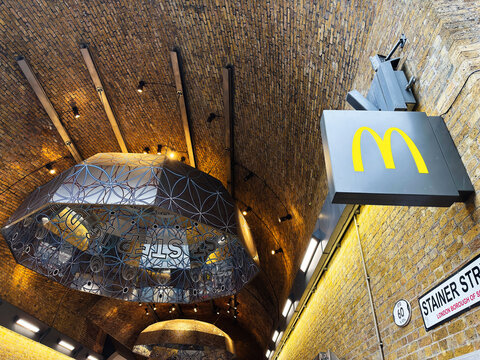 McDonald's sign under brick railway arch on Stainer Street in London UK with modern decorative ceiling lights