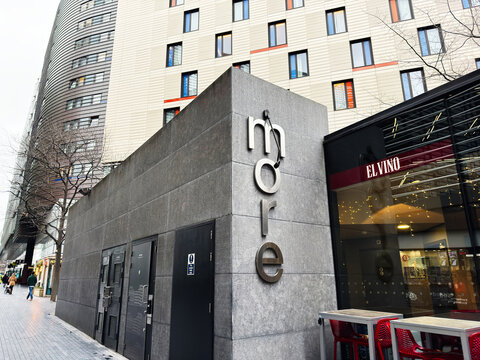 Modern urban building facade with more sign and El Vino cafe frontage in London, UK city street scene