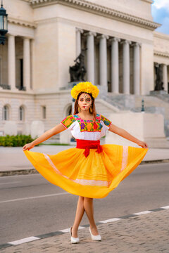 Latina woman performing a traditional dance with a colorful dress and Catrina makeup, celebrating the Day of the Dead in front of the Capitolio building in Havana
