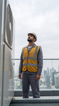 Skilled technician inspecting rooftop air conditioning unit above city skyline