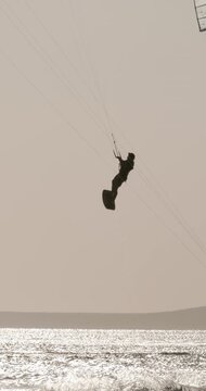 Kite boarder jumping high above the sea