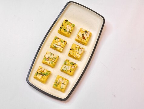 Soan papdi garnished with dry fruits plated on white plate