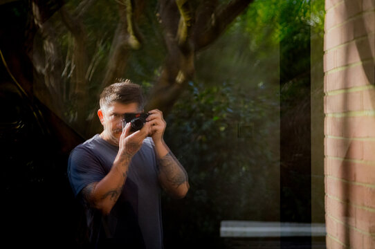 reflection of  a man taking a photo with a digital camera