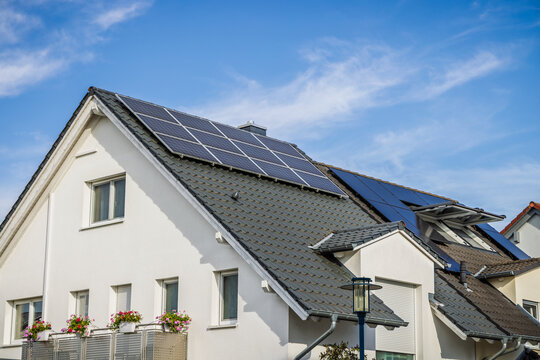 Modern residential house with solar panels installed on the roof under a blue sky