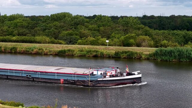 Cargo barge navigates Mittellandkanal in Germany under dramatic cloudy sky, representing inland freight transport. European waterway links major logistics routes toward Netherlands and Poland