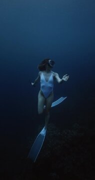 Freediver woman glides underwater in blue ocean