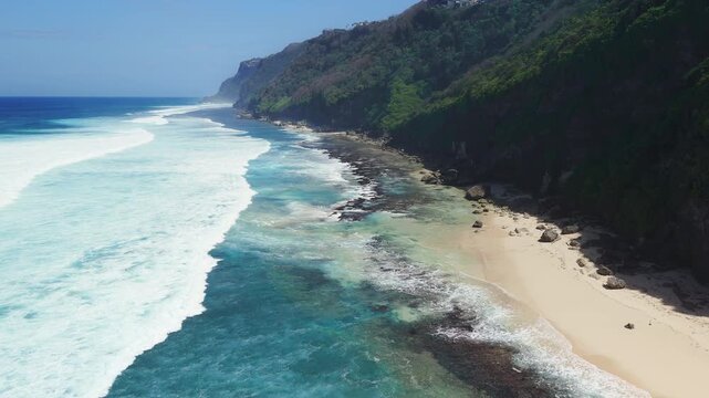 Scenic landscape with cliff coastline, sandy beach with blue ocean and waves. Aerial view