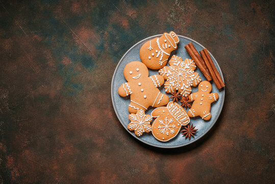 Collection of Christmas gingerbread cookies in a plate on a dark rustic background, top view, flat lay, copy space.