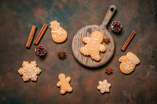 Various gingerbread cookies with cinnamon sticks and star anise on dark brown grunge background, top view, flat lay, Christmas.