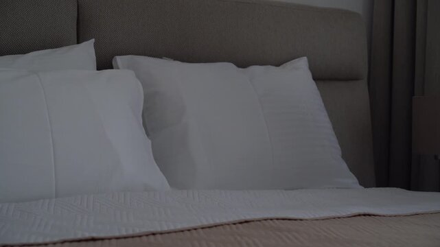 Woman arranging pillows on a bed in a cozy bedroom, home comfort and relaxing morning routine