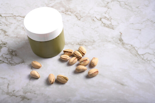 jar of creamy pistachio butter with whole nuts on marble surface, gourmet food concept, copy space