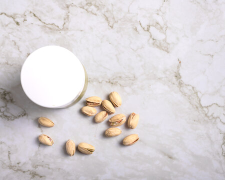 jar of creamy pistachio butter with whole nuts on marble surface, gourmet food concept, copy space