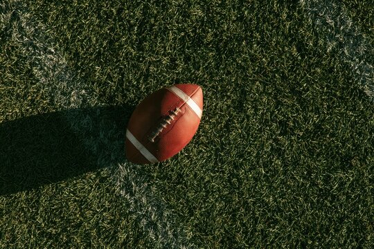 Overhead view of a single football on a grass field with ample copy space and autumn colors