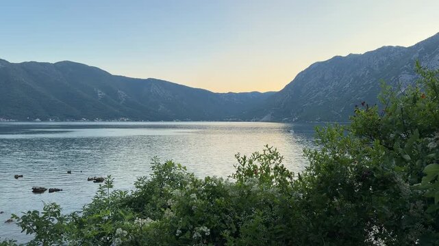 Scenic mountain bay at sunset, calm sea surrounded by dramatic peaks and warm golden evening light, peaceful coastal landscape