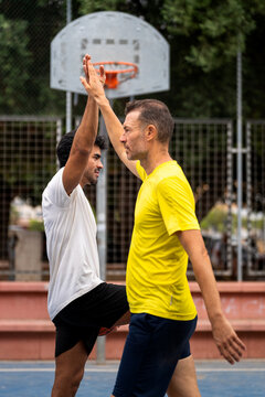 Friends playing basketball on court giving high five celebrating urban sport
