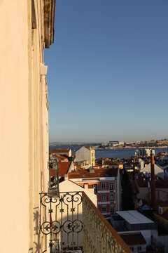 view of Lisbon, Portugal from a private balcony looking over rooftops towards Tagus River during late afternoon